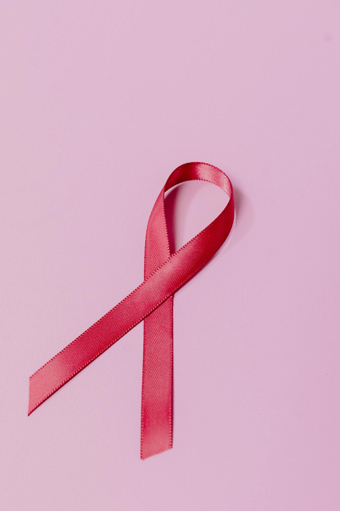 A pink ribbon on a pastel background symbolizing breast cancer awareness and support.
