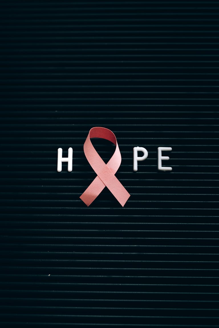 Close-up of a pink ribbon forming the word 'Hope' on a letter board.